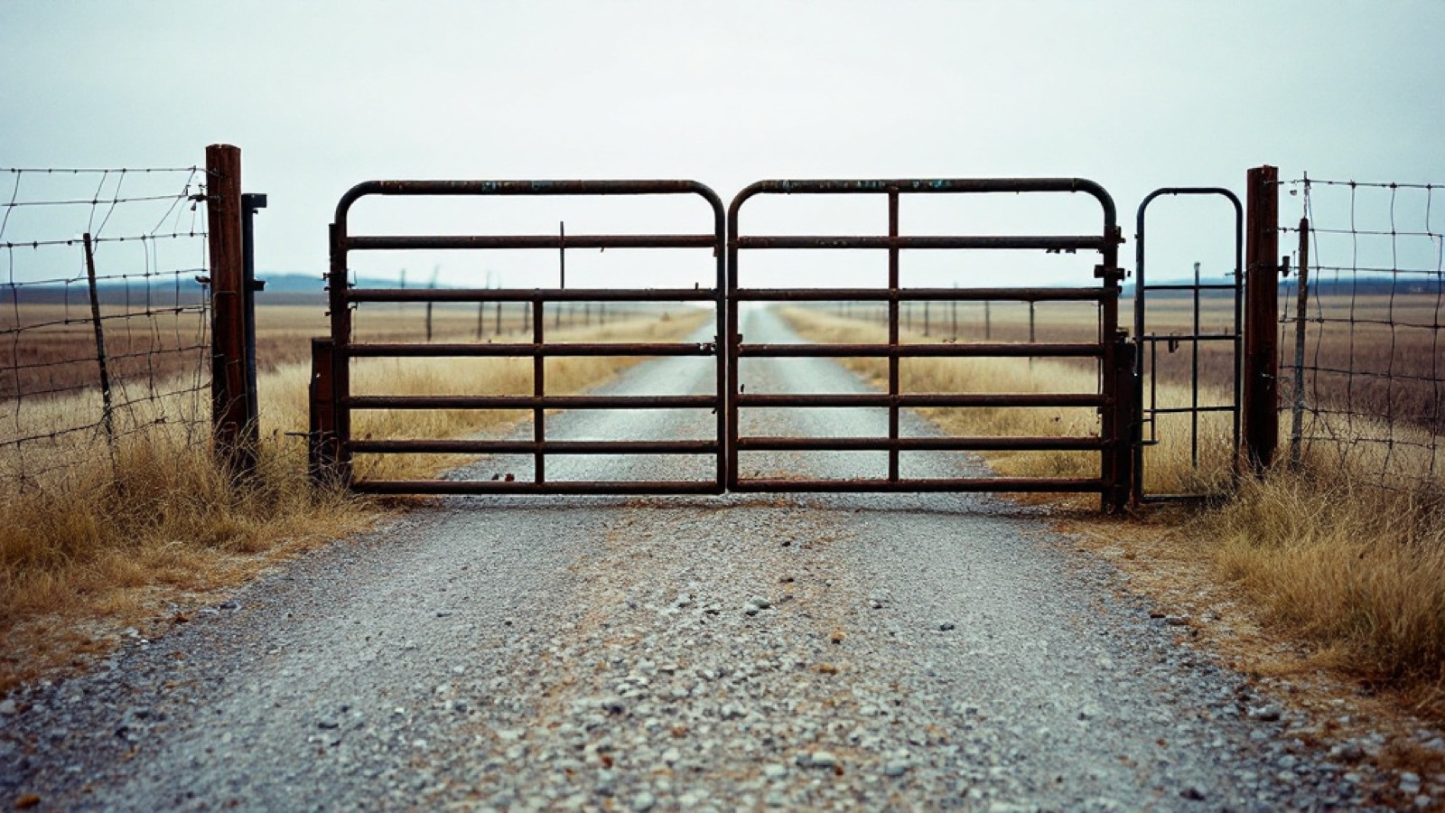 A cattle guard set in a ranch road with a wire fence
