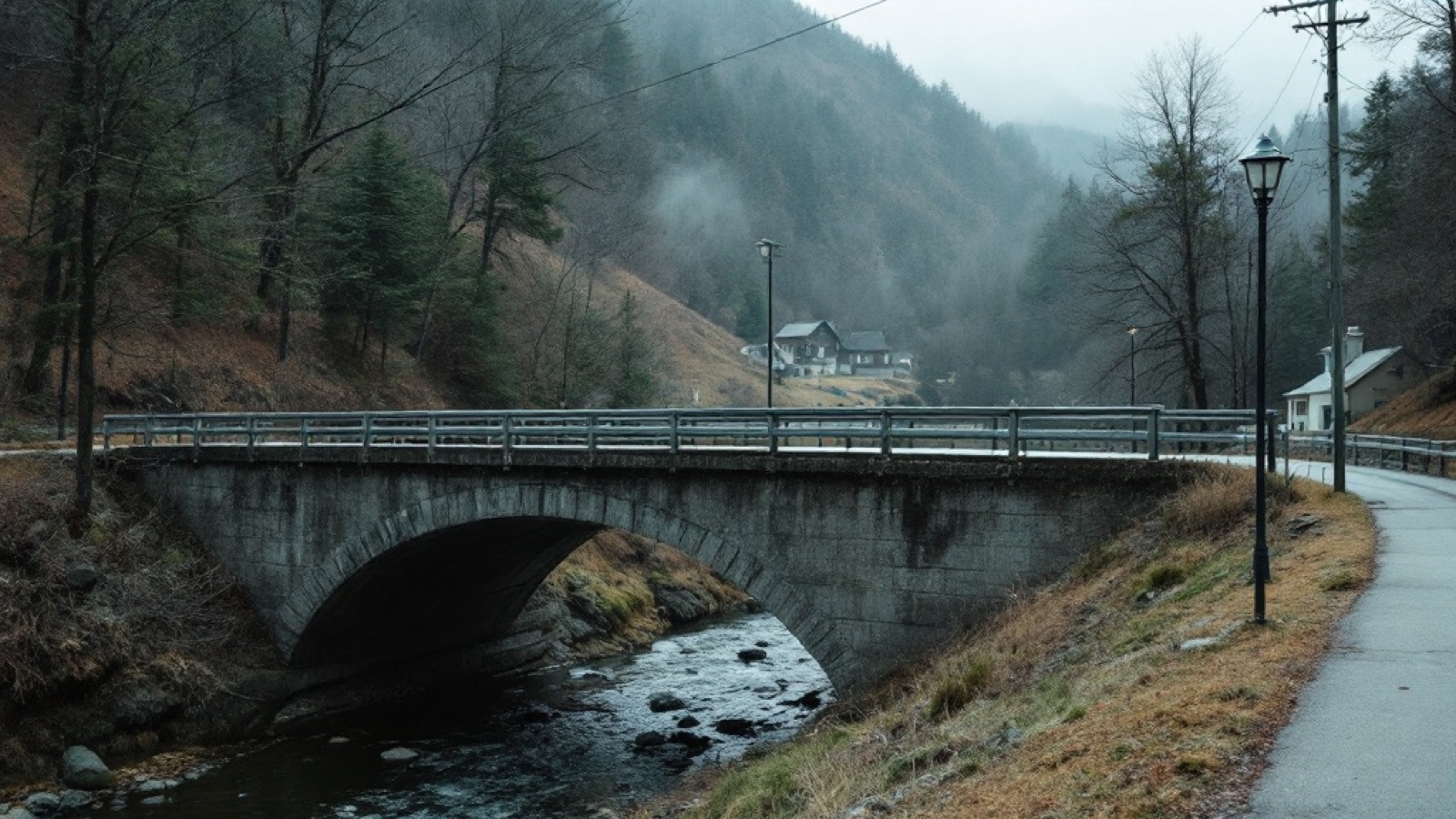A short concrete town bridge over a creek at the edge of a mountain community