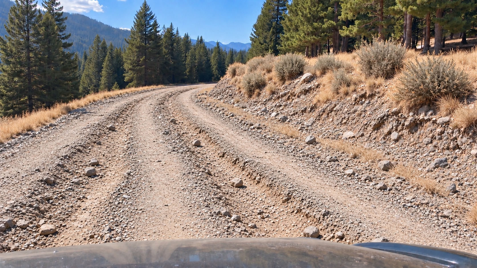 The same road at fire-season peak: dry, loose and rock-strewn, with ruts and washboard across the running surface.